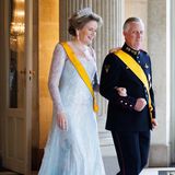 Mit einem strahlenden Lächeln im Gesicht betritt Königin Mathilde an der Seite von König Philippe den Saal. 