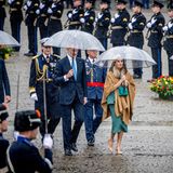 Kurz darauf verabschiedet sich die Sonne aus Amsterdam. Unter transparenten Regenschirmen schreiten König Felipe und Königin Letizia zur Kranzniederlegung am Nationaldenkmal.