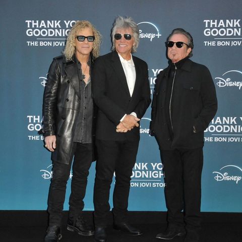 Jon Bon Jovi strahlt mit David Bryan (l.) und Tico Torres (r.) auf dem roten Teppich.