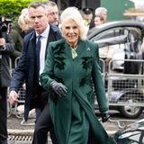 Windig geht's zu, als Königin Camilla eine Bäckerei in Belfast besucht. Und passend für diesen Besuch hat sie sich ein mit samtigen Blattmotiven besticktes Mantel-Kleid-Ensemble in Waldgrün ausgesucht.