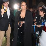 Auch Jennifer Lopez nutzt den Abend als modische Generalprobe und erscheint im schwarzen, schulterfreien Abendkleid, über das sie einen schwarzen Wollmantel geworfen hat.