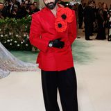 "The Gilded Age"-Star Morgan Spector bringt im rotglänzenden Blazer und XL-Mohnblüten am Revers Farbe auf den roten Teppich. Der Hingucker-Look mit weiter schwarzer Hose und Lederhandschuhen stammt vom Designer Willy Chavarria.