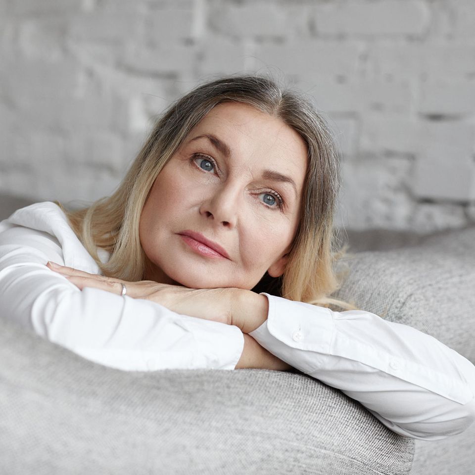 Ältere Frau schaut nachdenklich: 3 Faktoren, die unser Gehirn schneller und stärker altern lassen