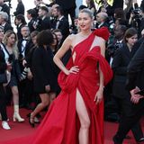 Perfektion! Das ist das Einzige, das einem beim Betrachten von Lena Gerckes Look für die Abschlusszeremonie der 77. Filmfestspiele in Cannes auffällt. Raffiniert wickelt sich der rote Stoff der ausladenden Robe um den durchtrainierten Körper des Models. Dabei werden Schultern, Taille und ein Bein gezielt ausgespart. 