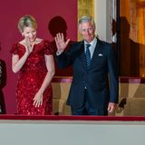 Auf seinen Plätzen angekommen winkt das belgische Königspaar den Gästen auf den unteren Rängen zu. 
