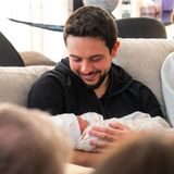 Glücklich lächelt der frisch gebackene Papa seine Tochter an, die in Tücher eingewickelt in seinem Arm liegt.