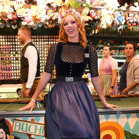 Beim Wiesn-Almauftrieb setzt Anna Ermakova auf Spitzenleistung. Ihr dunkelblaues Mieder aus Samt betont ihre Taille, während der Pünktchen-Rock ihr anmutige Süße schenkt. Gekonnt beherrscht das Model den Stilbruch mit verschnörkelten Stiefeln aus Leder und bringt den traditionellen Dirndl-Look so auf eine moderne Ebene.  0.6665