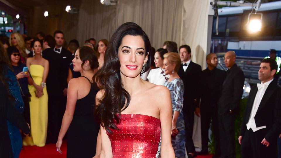 Amal Clooney überrascht bei einer Benefiz-Gala im roten Kleid mit Rüschen und Nieten.