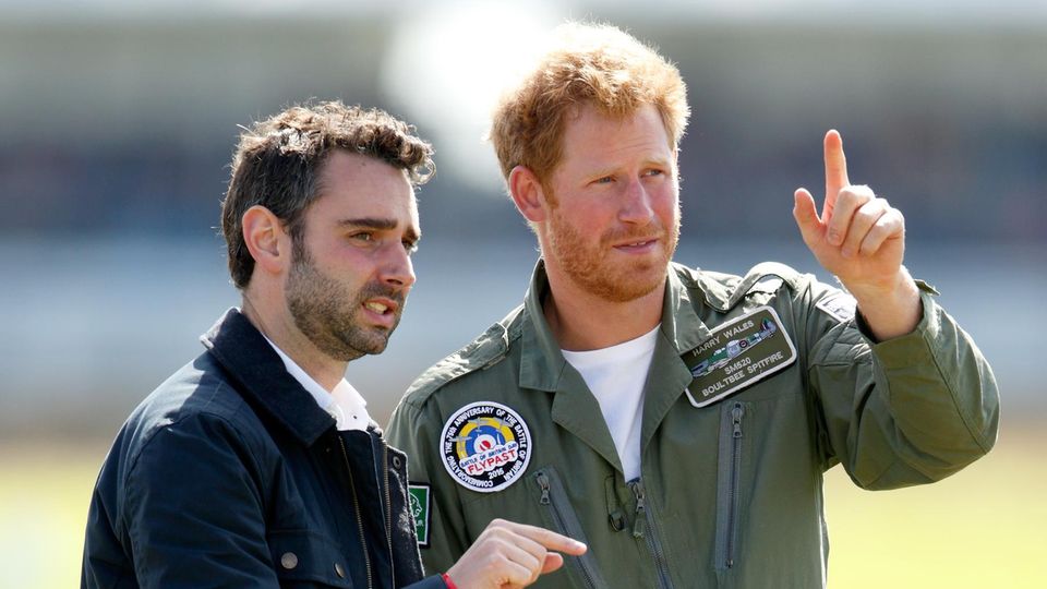 Prinz Harry unterhält sich mit Nick Loughran, dem stellvertretenden Pressesprecher von Prinz William und Herzogin Catherine sowie Harry selbst, während sie am 15. September 2015 auf dem Goodwood Aerodrome in Chichester, England, einen Battle of Britain Flypast besuchen. 