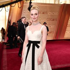 Weiße Spitze mit schwarzer Schleife: Elle Fanning erinnert wunderschön gestylt an Grace Kelly. Der Red-Carpet-Look stammt von Givenchy und wird mit Schmuck von Cartier noch glamouröser.