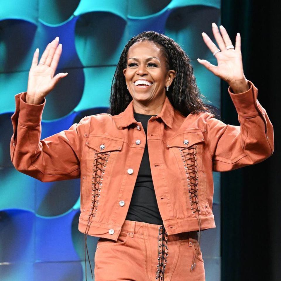 Bye bye Winter, hallo Frühling, scheint Michelle Obama mit ihrem orangefarbenen Zweiteiler bei ihrem Live-Auftritt einer Konferenz in Austin, Texas sagen zu wollen. Ihre Haare fallen ihr dabei lässig über die Schultern, während ihr schlichtes Make-up sie zum Strahlen bringt. Die Binde-Details an Jacke und Hose sind eine kleine Überraschung und erinnern an die Looks von Christina Aguilera aus den 2000er-Jahren.