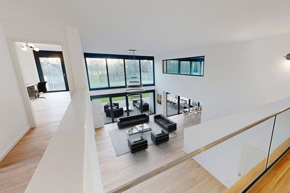 Das großzügig geschnittene Wohnzimmer im Haupthaus erstreckt sich über zwei Etagen und lässt so jede Menge Licht ins Haus. Ein cleanes, hauptsächlich in Schwarz und Weiß gehaltenes Interieur gibt Raum für Ruhe und Entspannung.