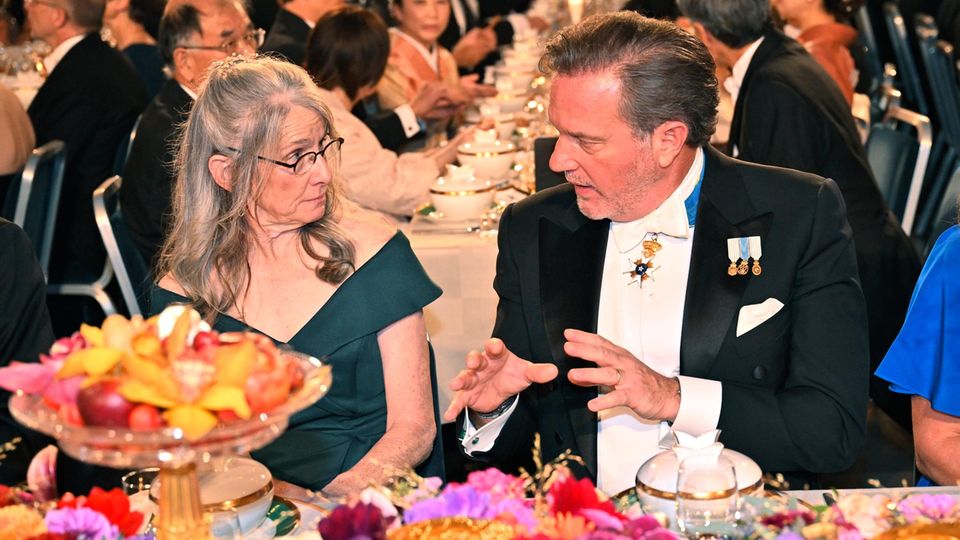 Beim angeregten Gespräch mit Laura O’Neill blitzt unter dem linken Ärmel von Chris der Ansatz seiner Rolex hervor. Ein No-Go beim Nobelpreis? 