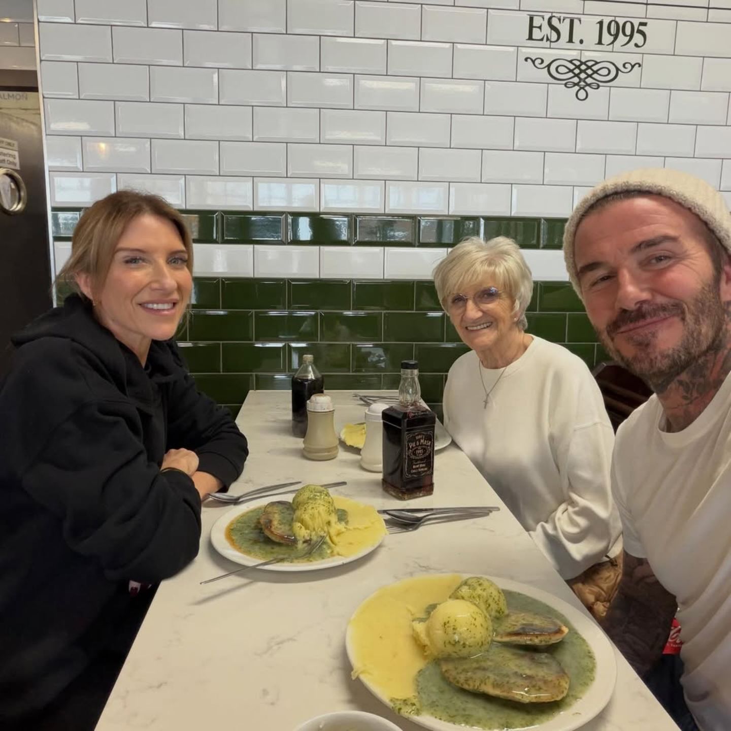 "Für die Seele gibt es nicht Besseres als Pie & Mash mit meiner Mama", kommentiert David Beckham sein Lunch-Date. Der britische Mahlzeitenklassiker besteht typischerweise aus einer Hackfleischpastete, die mit Kartoffelpüree und einer Petersiliensauce gereicht wird. Das weckt Kindheitserinnerungen! Auch Joanne Beckham, Davids jüngere Schwester, lässt sich dieses Essen nicht entgehen und nimmt ebenfalls am Familientisch im Restaurant "Tony's Pie & Mash" Platz – einem von David Beckhams absoluten Lieblingsläden nahe London. Dieses Treffen nährt also Leib und Seele.