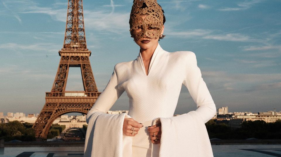 Zendaya posiert mit ihrer außergewöhnlichen Maske vor dem Pariser Eiffelturm.